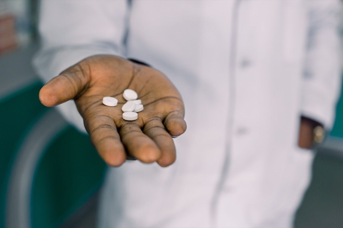 Мужчина держит таблетки, лекарства или витамины