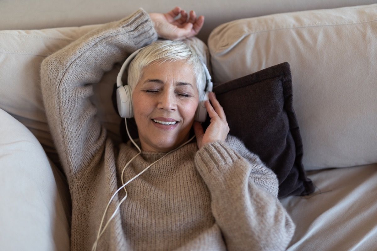 по-възрастна бяла жена, слушаща музика в леглото