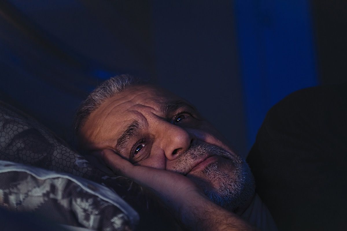 Старши мъж в средата на нощта с отворени очи и набраздени вежди
