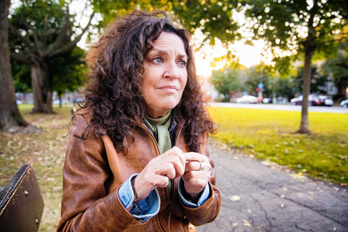 Angstige vrouw van middelbare leeftijd in crisis buiten in park op een middag buiten