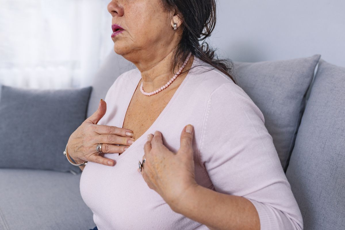 Mulher madura de meia-idade, estressada e chateada, sentindo dor e dor no peito, pode estar tendo um ataque cardíaco ou derrame