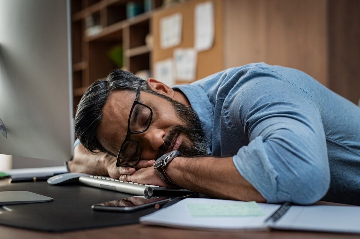 Väsynyt monietninen liikemies nukkuu toimistossa