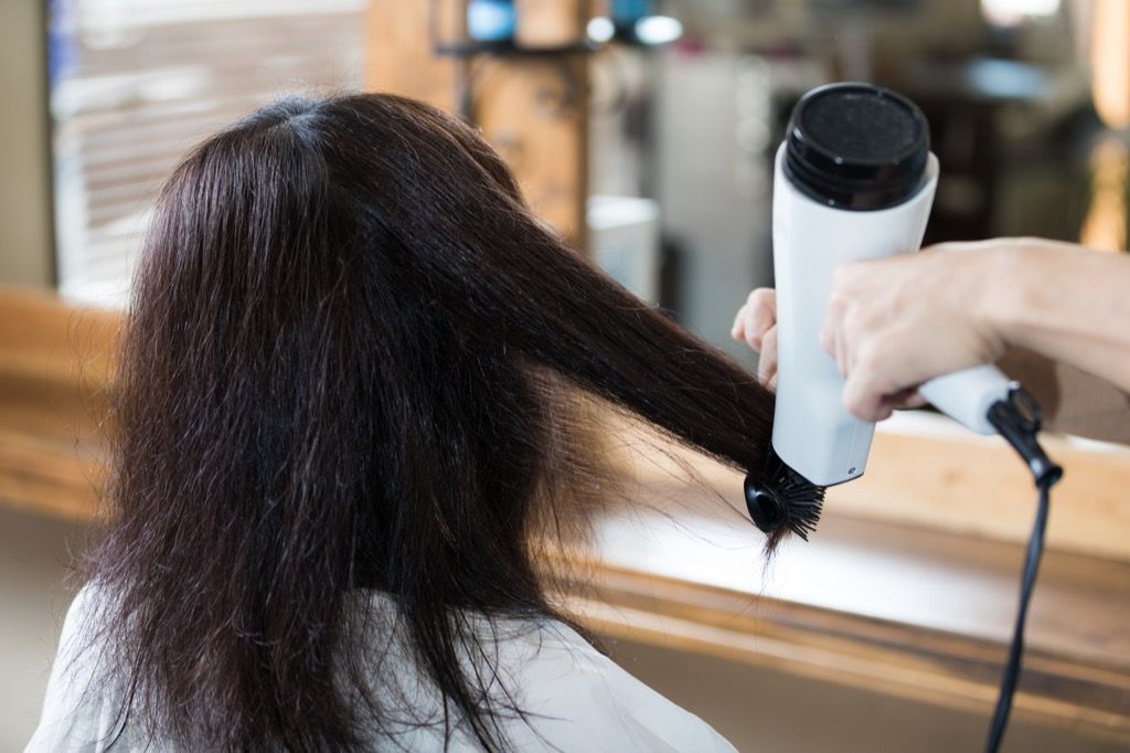 une femme coiffant ses cheveux à la chaleur - paraître plus jeune