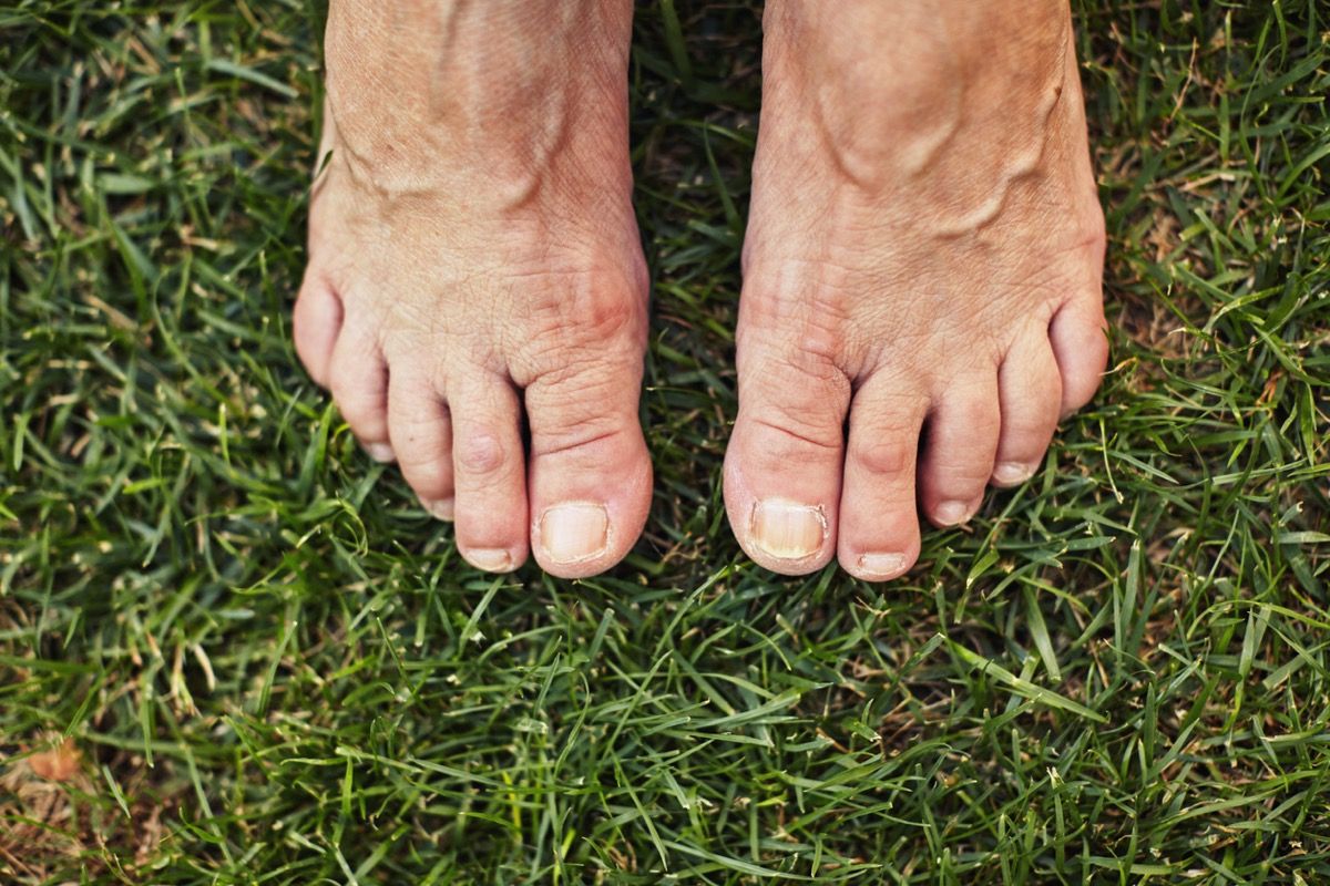 Senior descalzo de pie sobre la hierba verde