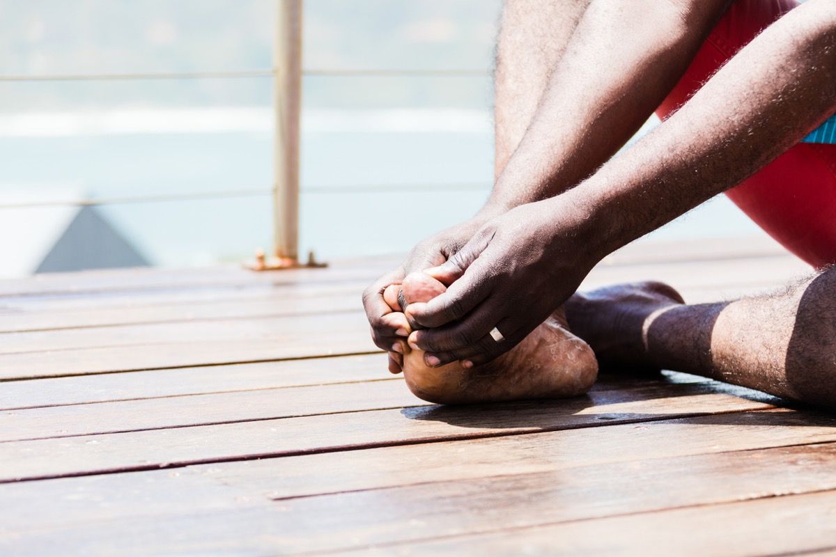 एक अफ्रीकी व्यक्ति अपने बड़े पैर की अंगुली पकड़ता है