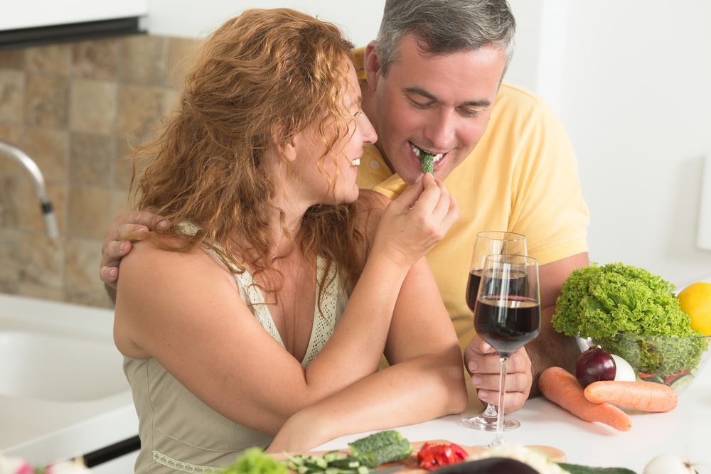 бяла жена, хранеща зеленчук на бял мъж с вино