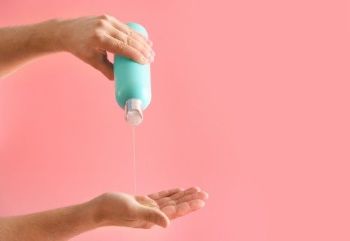 valkoinen käsi kaatamalla shampoota pullosta