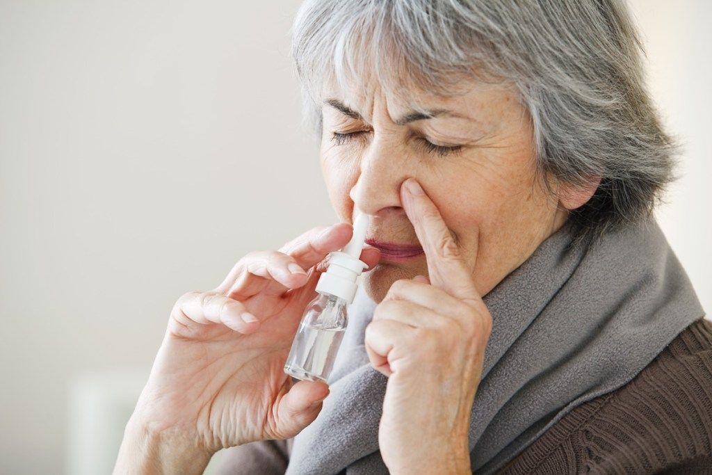 Жена, използваща спрей против деконгестант за настинка