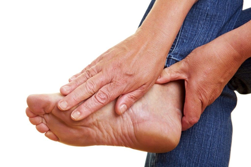 Femme se frottant le pied dans les symptômes de la douleur du cancer