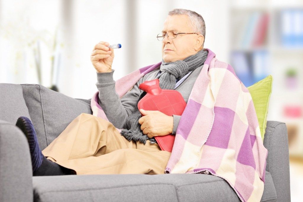 Eldre mann syk på sofaen med feber