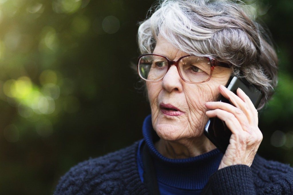 ældre kvinde ser ængstelig ud, mens hun taler i telefon