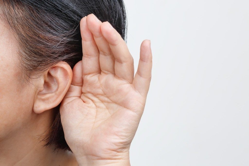 mujer con cabello gris ahuecando su oreja porque tiene problemas de audición