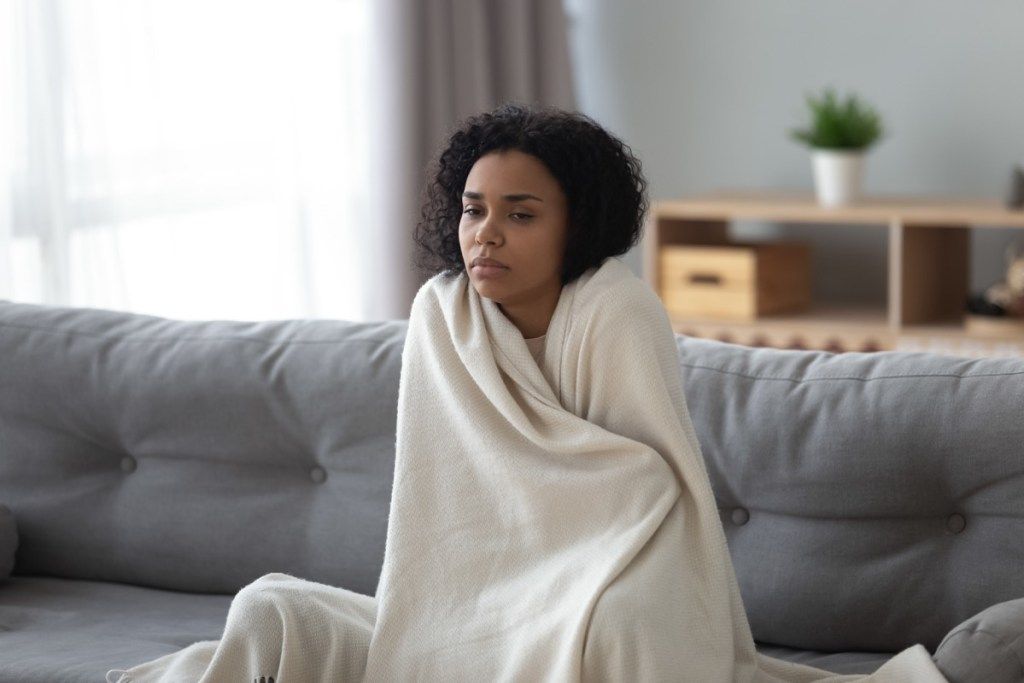 Жена дрхти под покривачем јер јој је тако хладно