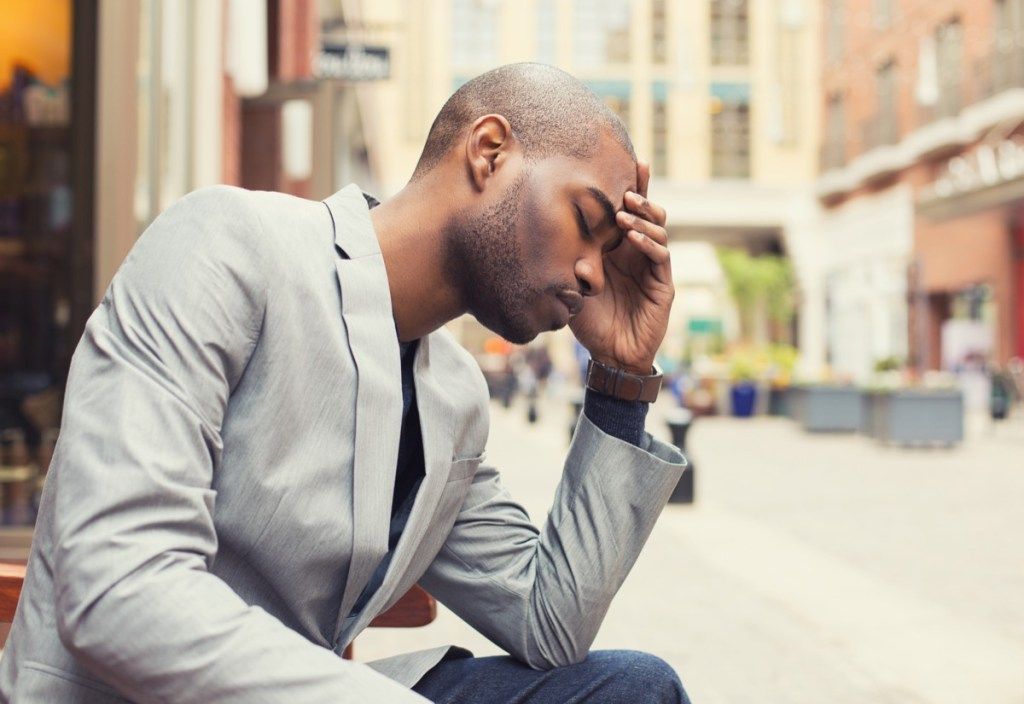 Мъж, който държи главата си с главоболие Тихи здравни симптоми