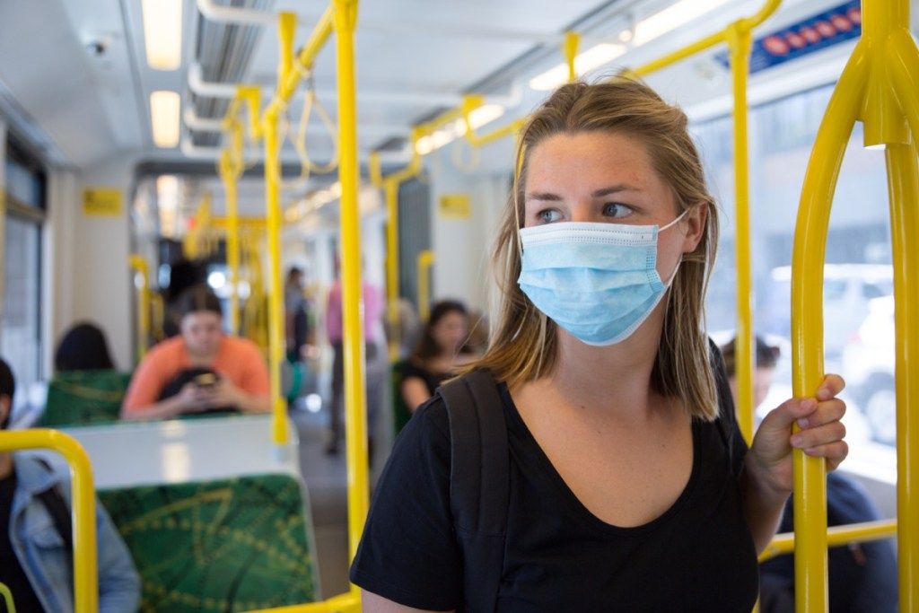 nő eldobható maszkot visel a tömegközlekedésen koronavírus-járvány idején