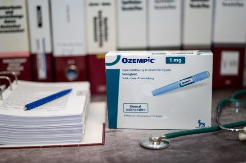   Semaglutiidi sisaldav Ozempici ravimikarp 2. tüüpi diabeedi raviks ja pikaajaliseks kaalujälgimiseks laual ja taustal erinevad meditsiiniraamatud.