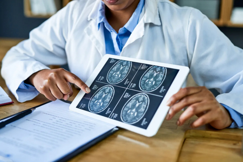   Gydytojas naudoja skaitmeninę planšetę, kad aptartų smegenų skenavimą.