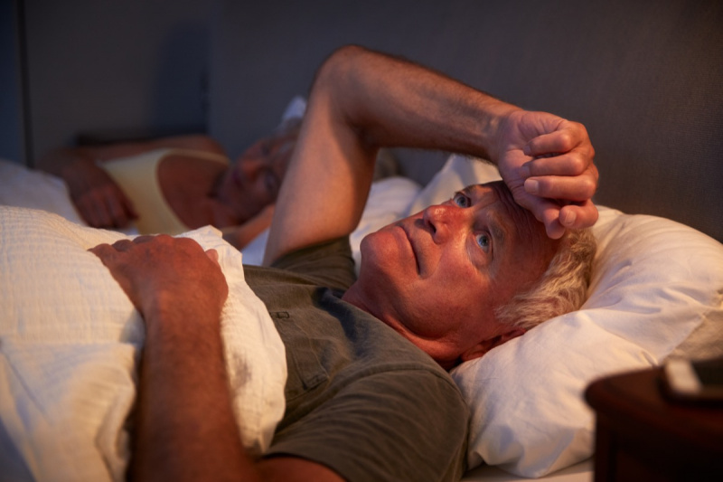   starszy mężczyzna z siwymi włosami budzi się w łóżku w nocy