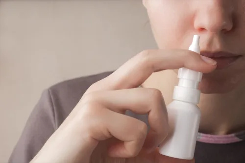   Žena koristi sprej za nos