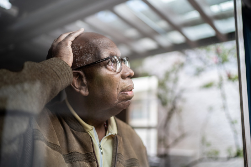   възрастен мъж с деменция, гледащ през прозореца