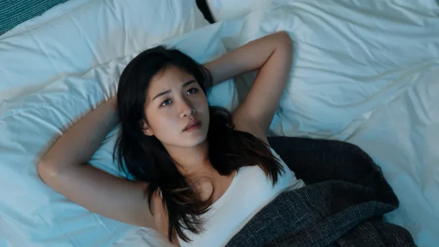   หญิงสาวชาวเอเชียนอนอยู่บนเตียงดูกังวลและสามารถ't fall asleep