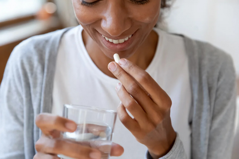   Kvinna som tar medicin med vatten.