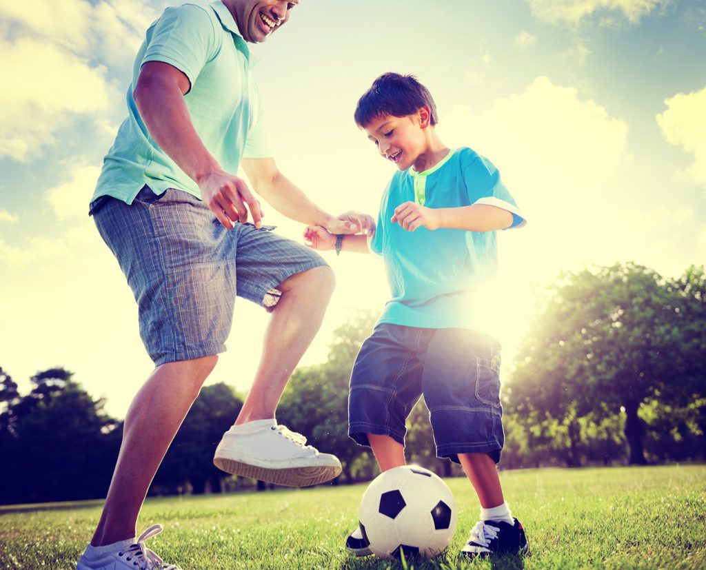 Père et fils jouant au football parental