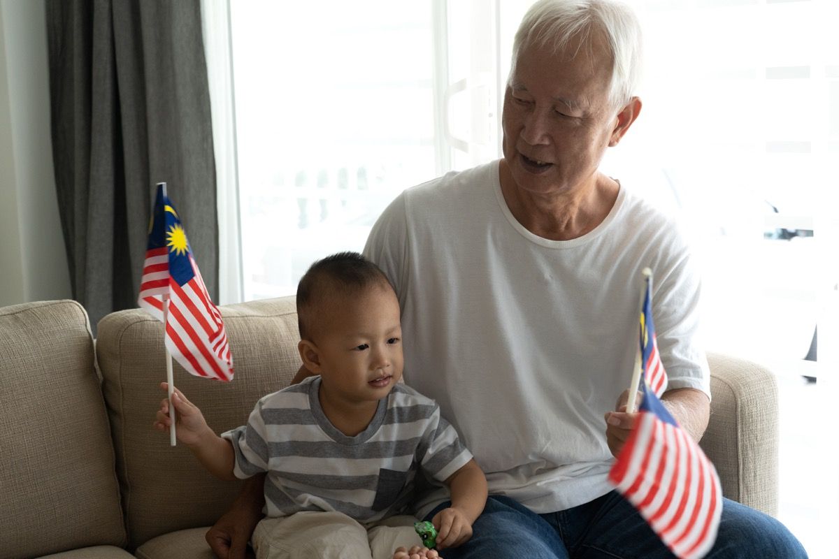 Дядо с внук, държащ малайзийски знамена