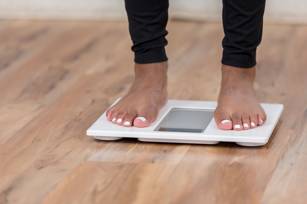 Mujer que se pesa en una báscula para determinar la posible pérdida o aumento de peso