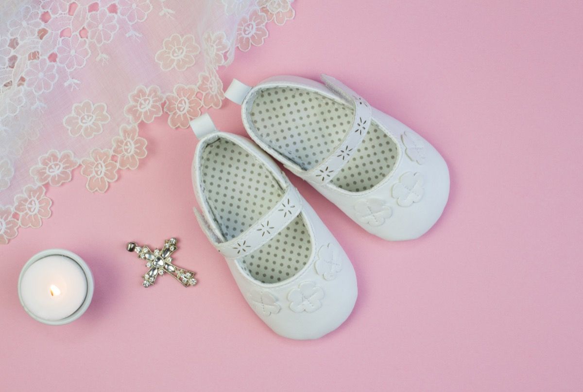 फीता पृष्ठभूमि पोशाक और मोमबत्ती के साथ गुलाबी पृष्ठभूमि पर सफेद बच्चे की बूटियों की जोड़ी