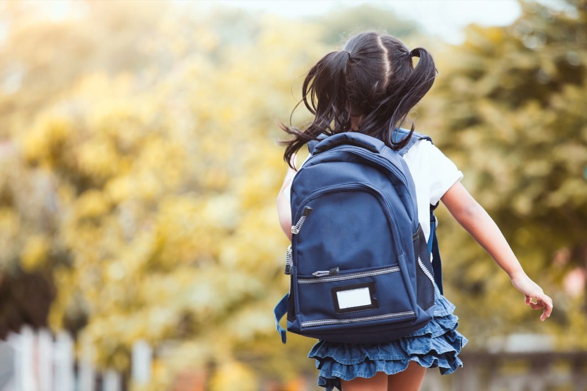 Atgal į mokyklą. Miela azijiečių vaikų mergaitė su kuprine bėga ir eina į mokyklą linksmai