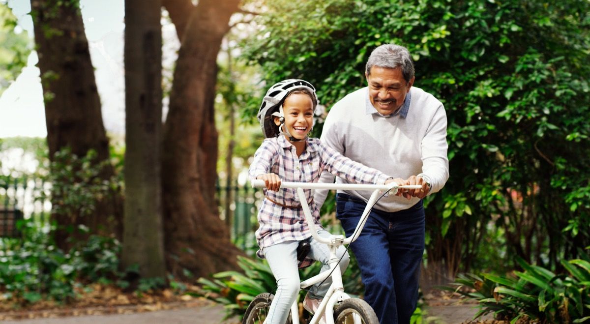 abuelo enseñando a su nieta a andar en bicicleta afuera