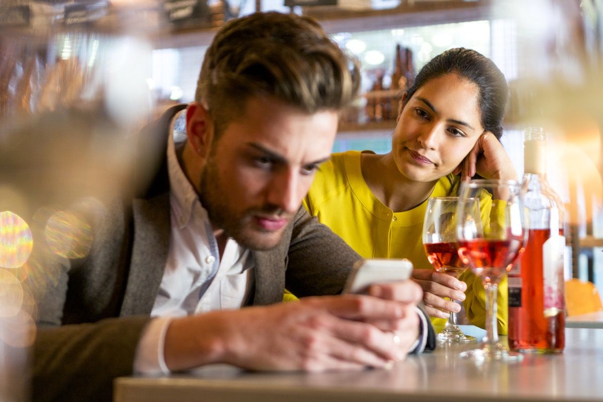 ungt par på en date med manden på hans telefon, der ignorerer den irriterede kvinde