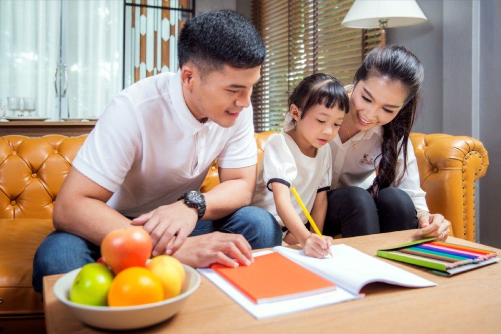 asiatiske foreldre som hjelper små barn med lekser, er stiforelder
