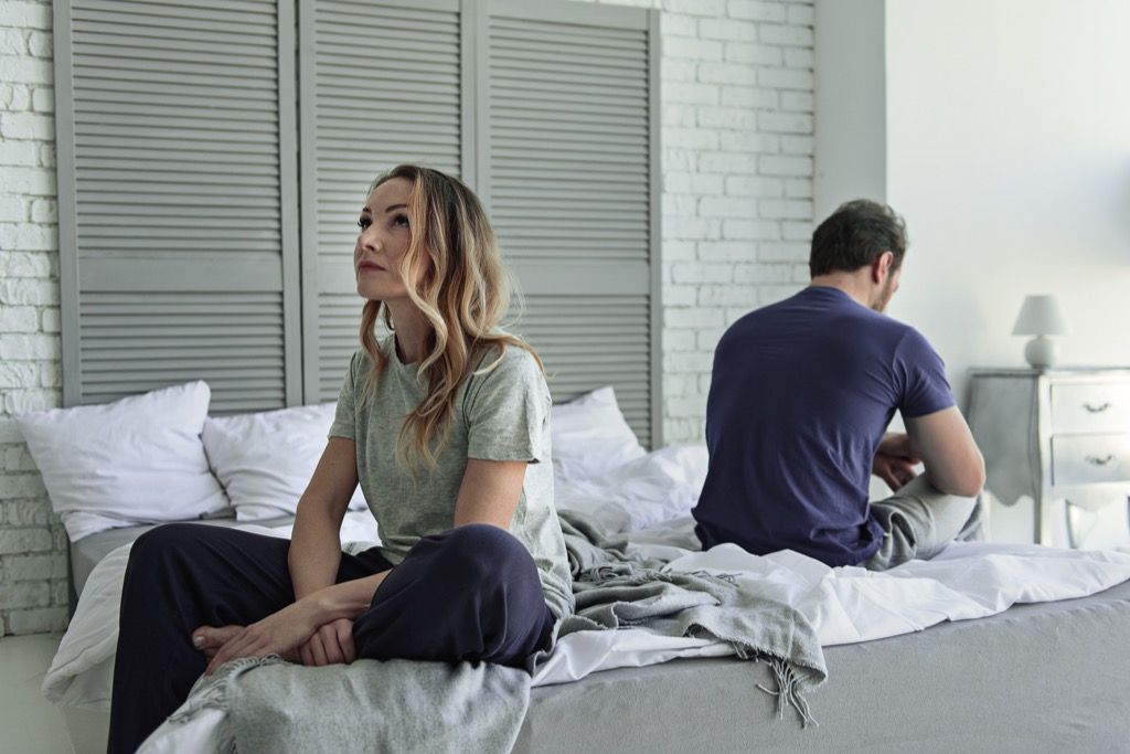 Два человека переживают развод, сидя на кровати