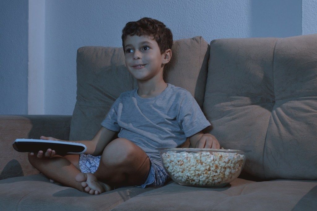 Enfant regardant la télévision et mangeant du pop-corn tard dans la nuit se trouve ex-conjoints