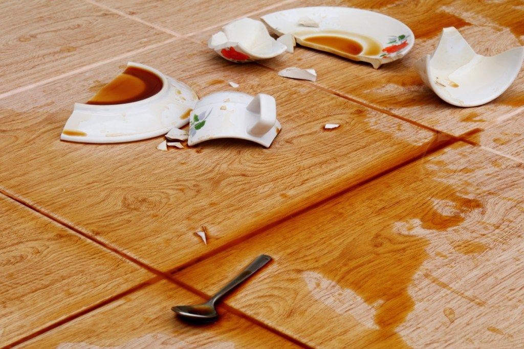 sulūžusios lėkštės ir puodelis ant grindų