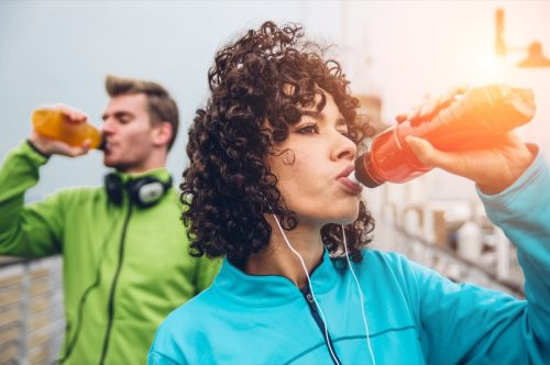   Мъж и жена пият енергийна напитка от бутилка след фитнес спортно упражнение