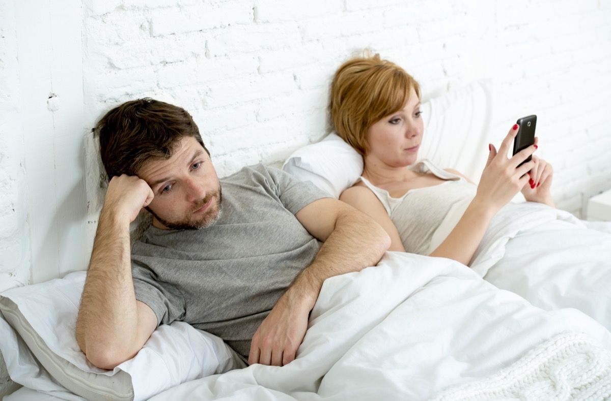 Pāris gultā nerunājoša sieviete īsziņu sūtīšana vīrietis garlaicīgi