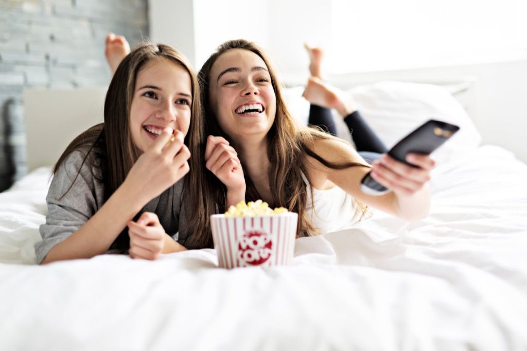 adolescenți care se uită la filme în pat