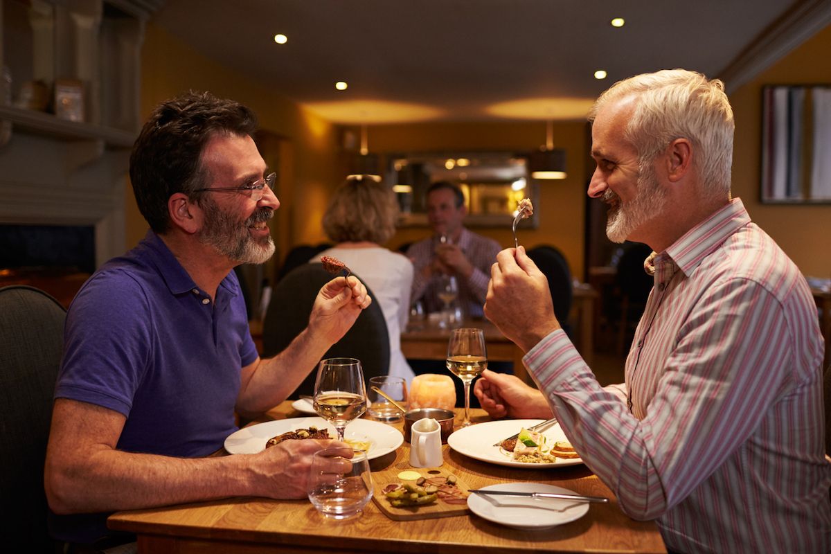 Vidutinio amžiaus vyrų gėjų pora valgo vakarienę restorane