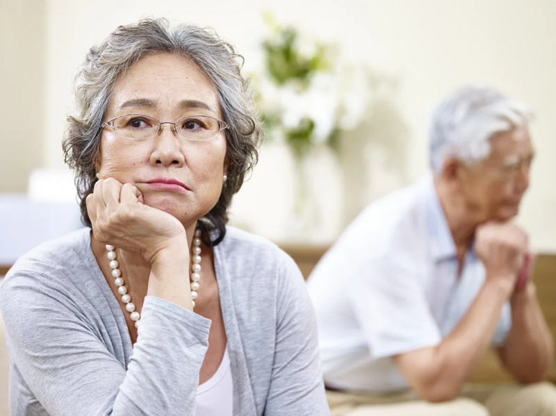   старша азиатска двойка, седнала на дивана у дома, ядосана един на друг