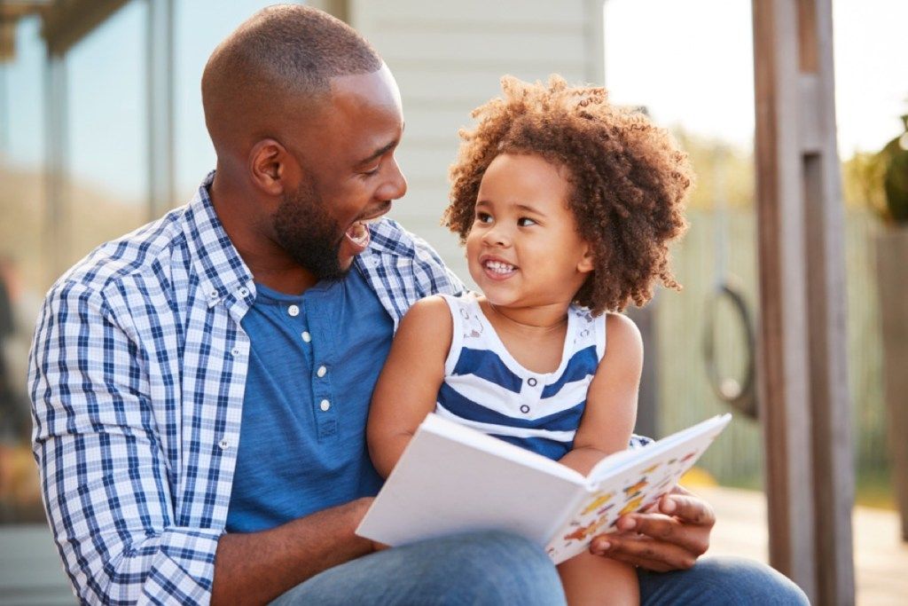 татко чете книга на малката си дъщеря, подготвя децата за развод