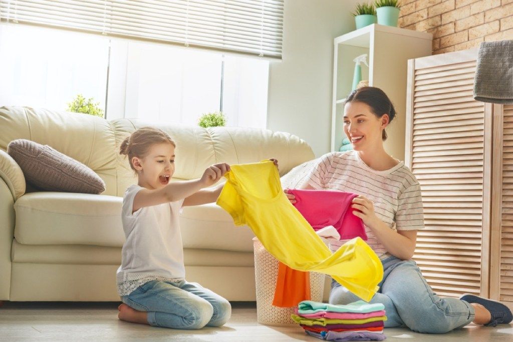 младо момиче и майка сгъваемо пране, подгответе децата за развод
