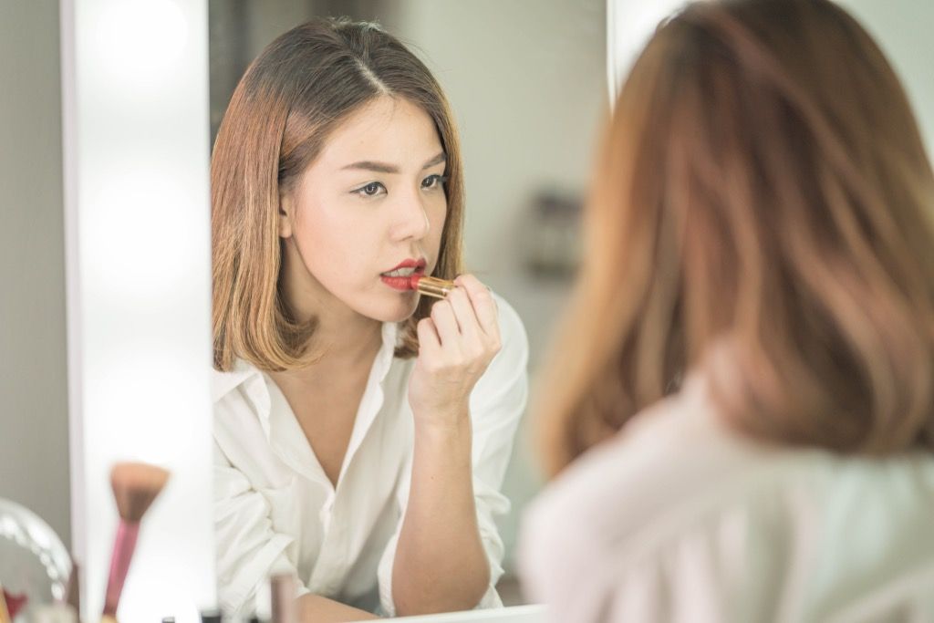 kvinde anvender læbestift i et spejl