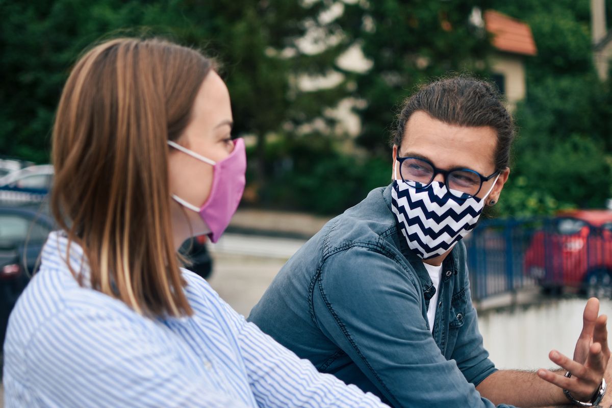 Младић и девојка носе маске напољу и разговарају