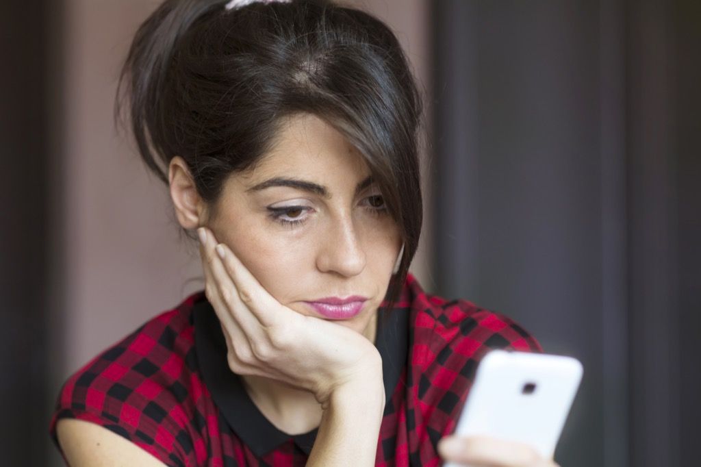 sklamaná žena čítajúca telefónne potvrdenie