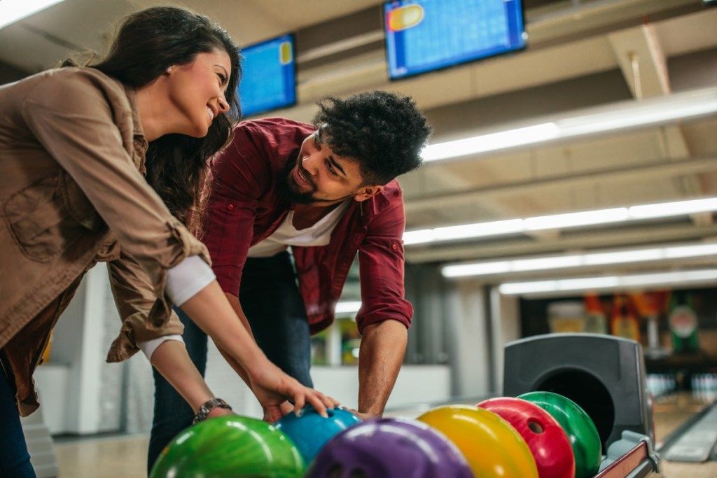 pasangan muda antar ras bermain bowling bersama