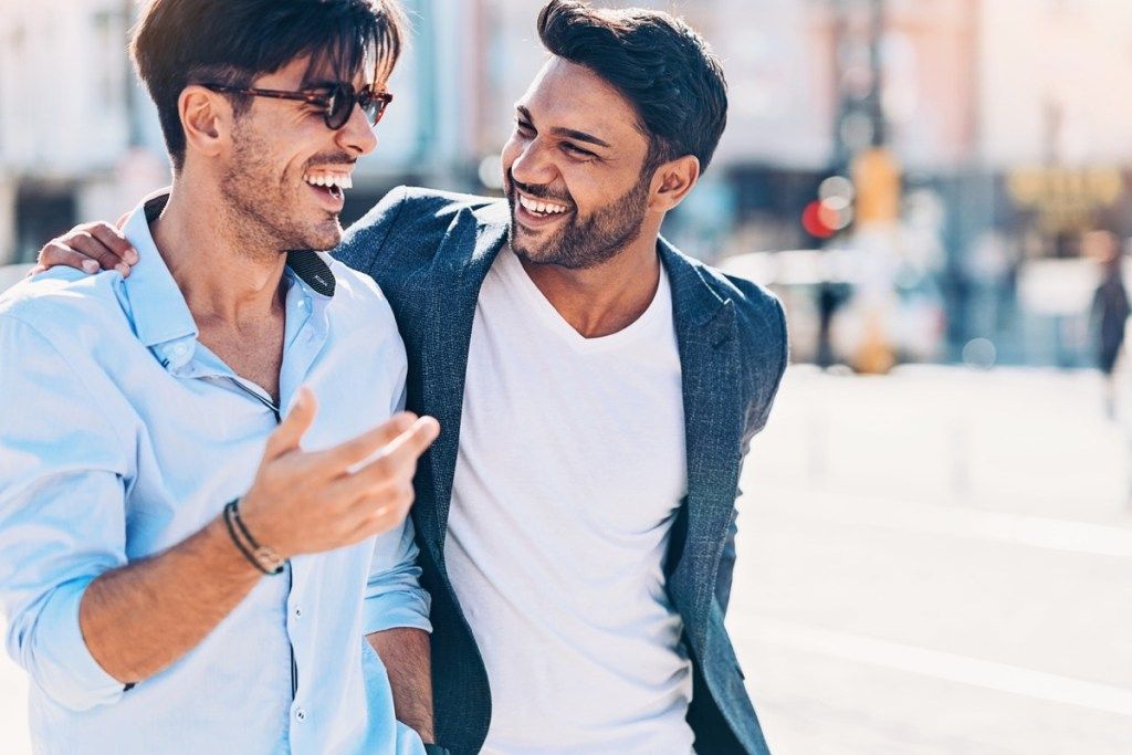två unga indiska män skrattar tillsammans på gatan