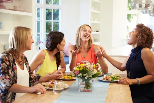   vier vrouwen lachen en eten op een etentje